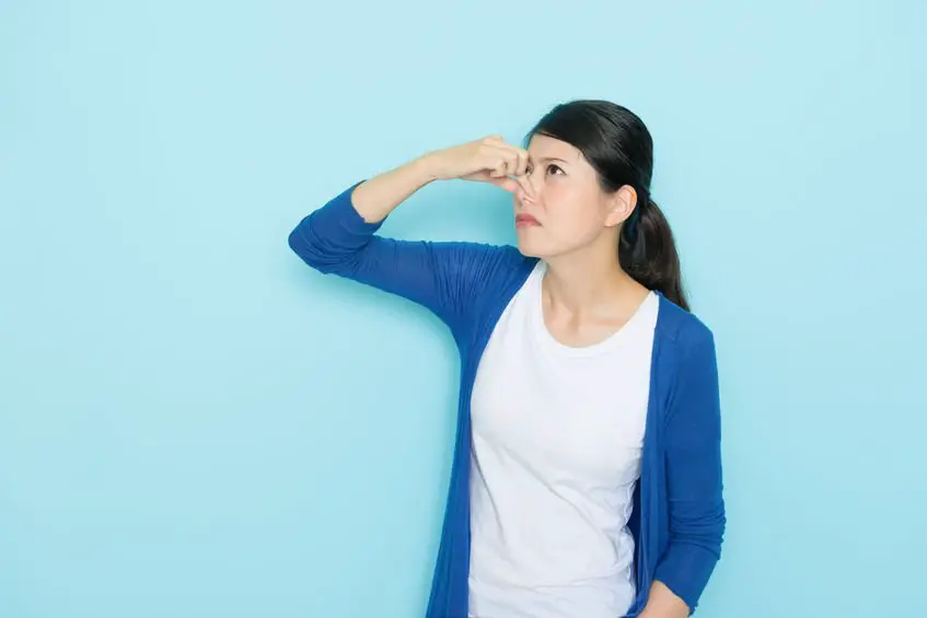 woman smelling bad paint using hands closing nose